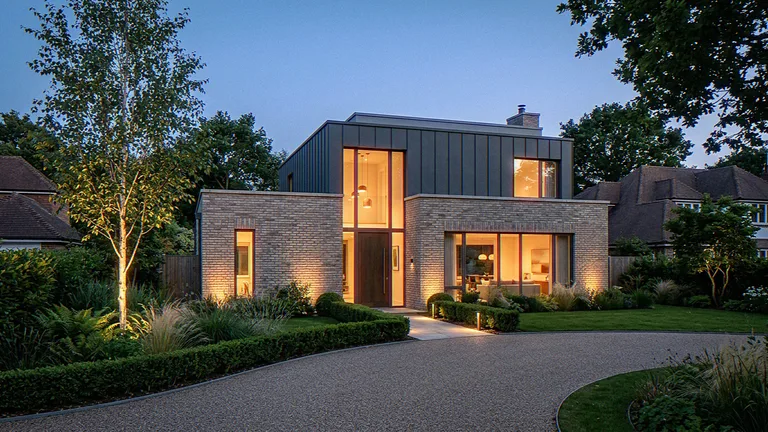 Exterior CGI of a contemporary detached house at dusk, brick base, dark clad upper storey and lit entrance glazing